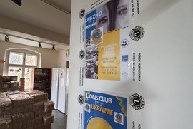 Na zdjęciu widać drzwi na których znajdują się plakaty informujące o pomocy na Ukrainie. W tle widać pomieszczenie z rozmieszczoną żywnością. (photo)