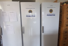 Na zdjęciach widać trzy lodówki. Na dwóch z nich widnieją naklejki z logo: Lions Club International. Na trzeciej lodówce powieszone są kartki. (photo)