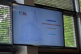 Zdjęcie przedstawia ekran telewizora z wyświetloną informacją o I posiedzeniu Leszczyńskiej Rady Seniorów Trzeciej Kadencji . W jego tle znajduje się okno.  (photo)