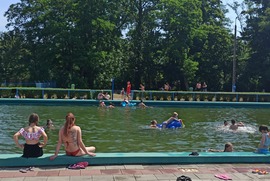 Zdjęcie przedstawia ludzi spędzających czas w i przy basenie. (photo)