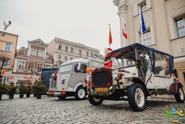 Zdjęcie przedstawia dwa przystrojone świątecznie auta. Z tle widać choinki (photo)