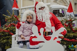 Zdjęcie przedstawia dziewczynkę pozującą z Mikołajem w świątecznej scenerii (photo)