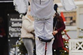 Zdjęcie przedstawia mężczyznę w stroju anioła, jeżdżącego na monocyklu (photo)