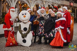 Zdjęcie przedstawia pozującą grupę ludzi wraz z Mikołajem i bajkową postacią na tle ogródka wiedeńskiego (photo)