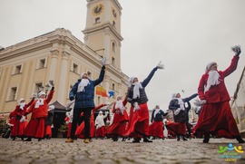 Zdjęcie przedstawia grupę tańczących ludzi na tle Ratusza (photo)