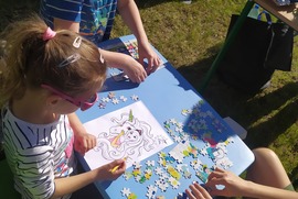 Zdjęcie przedstawia dzieci układające puzzle i kolorujące obrazki przy stoliku. (photo)