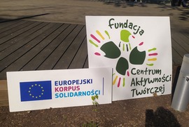 Zdjęcie przedstawia stojące przed sceną dwa banery, Fundacji Centrum Aktywności Twórczej oraz Europejskiego Korpusu Solidarności. (photo)