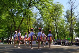 Zdjęcie przedstawia dziewczyny tańczące w strojach mażoretek. Dziewczyny ubrane są w białe bluzki i kolorowe spódniczki. (photo)