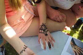 Zdjęcie przedstawia stoisko przy którym można było namalować sobie tatuaż z henny. Na zdjęciu widać pomalowane henną ręce. (photo)