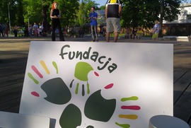 Zdjęcie przedstawia dwie osoby znajdujące się na scenie. Osoby te żąglują piłeczkami. Na pierwszym planie widać baner Fundacji Centrum Aktywności Twórczej. (photo)
