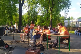 Zdjęcie przedstawia scenę, na której znajduje się grający i śpiewający zespół. W tle widać drzewa. (photo)