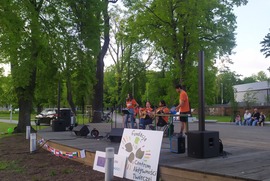 Zdjęcie przedstawia scenę, na której znajduje się grający i śpiewający zespół. W tle widać drzewa. (photo)