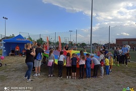 Zdjęcie przedstawia dzieci uczestniczące w Miejskim Dniu Dziecka, bawiące się chustą klanzą. (photo)