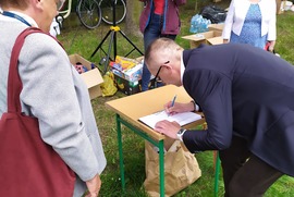 Zdjęcie przedstawia Prezydenta Miasta podpisującego listę. Koło niego stoi Radna Miasta Leszna (photo)