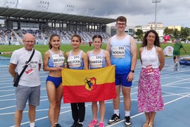 Zdjęcie przedstawia szóstkę ludzi trzymających flagę Leszna, stojących na stadionie lekkoatletycznym.  (photo)