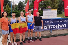 Zdjęcie przedstawia piątkę ludzi, trzymających flagę Leszna, w ich tle  widać banery reklamowe, balony oraz zieleń. (photo)